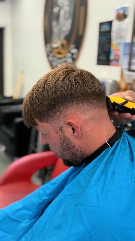 A barber at Infinity Barbers mid-cut with clippers